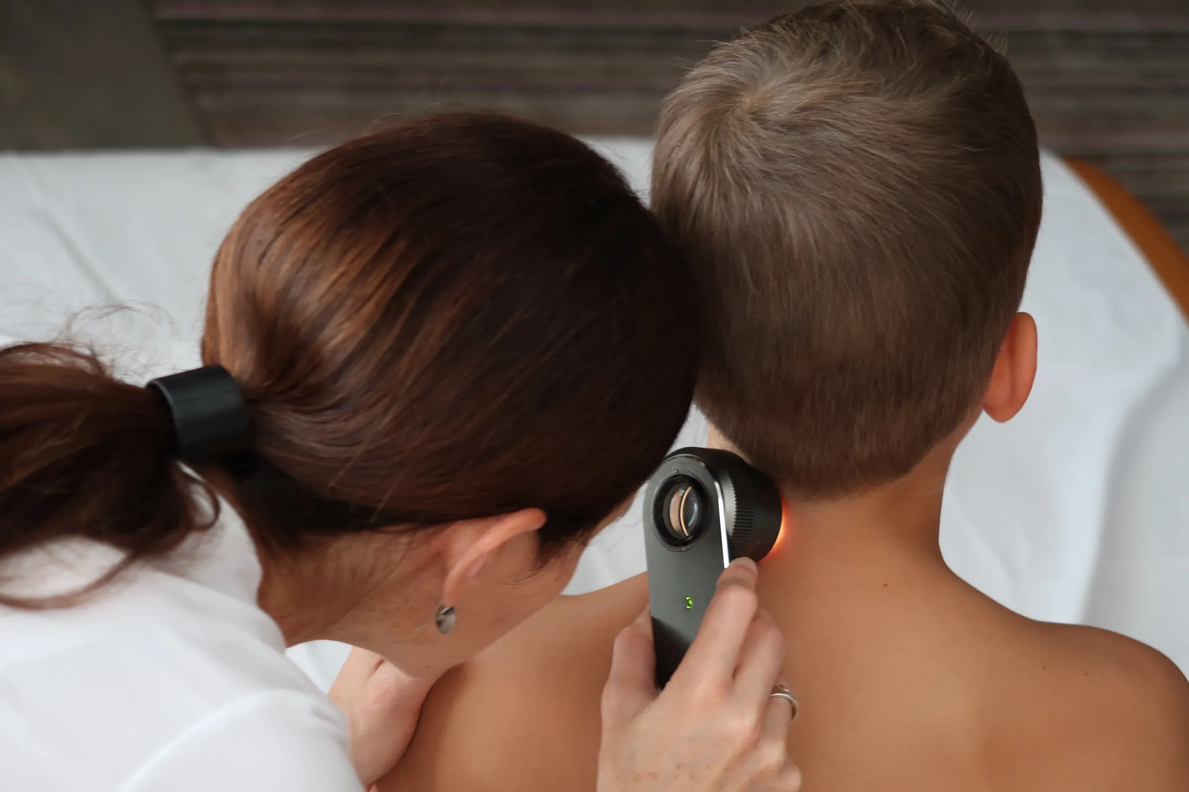 Dr. Siklós Krisztina dermatoszkóppal vizsgálja egy gyermek hátán lévő anyajegyet